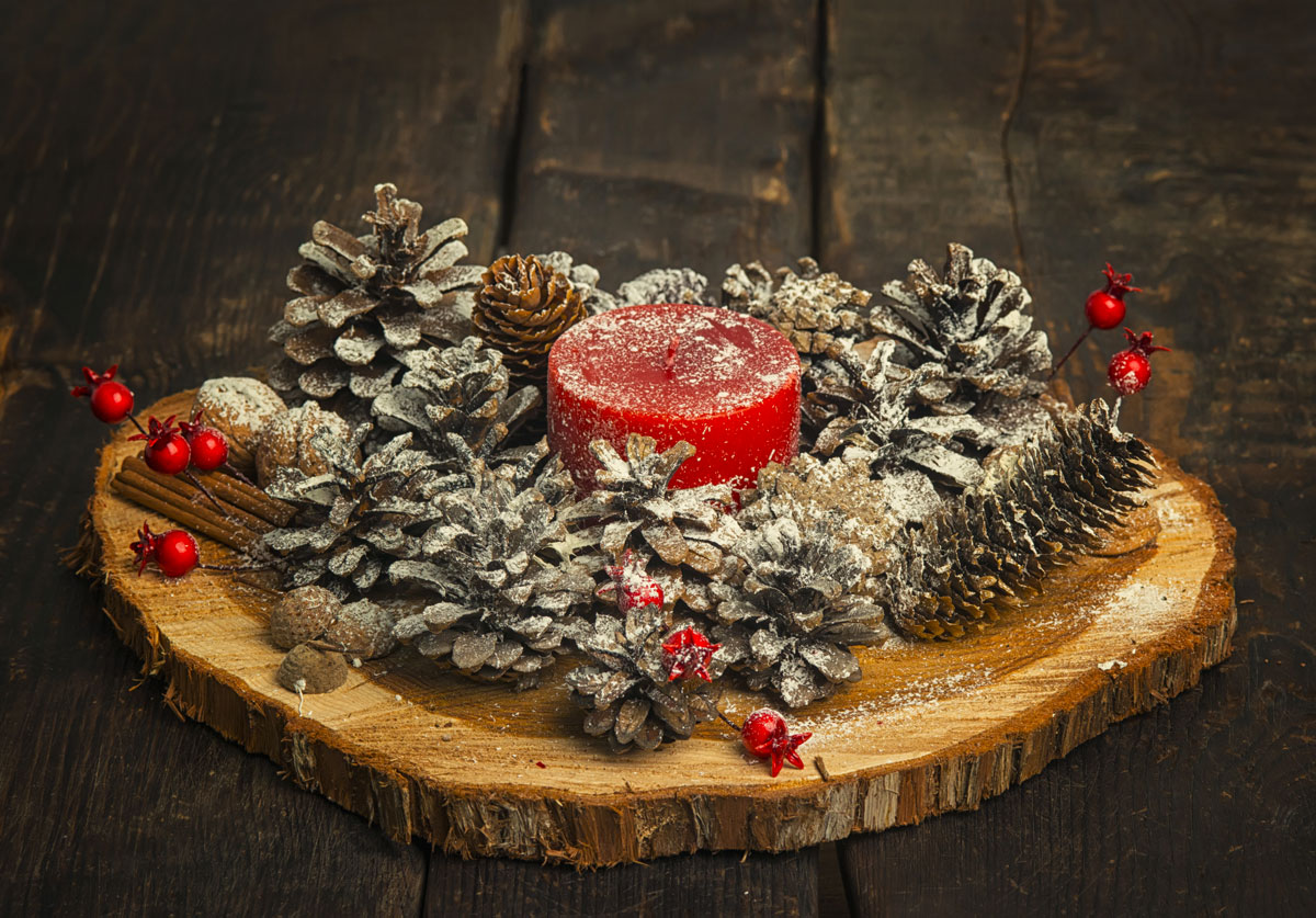 Centrotavola natalizio fai da te con candele rosse, pigne e tronco di legno